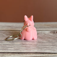 Back of a 3D printed pink bunny-shaped keychain on a wooden surface