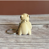Back of a 3D printed beige capybara-shaped keychain on a wooden surface