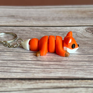 Side of a 3D printed orange fox-shaped keychain on a wooden surface