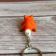 Back of a 3D printed orange fox-shaped keychain on a wooden surface