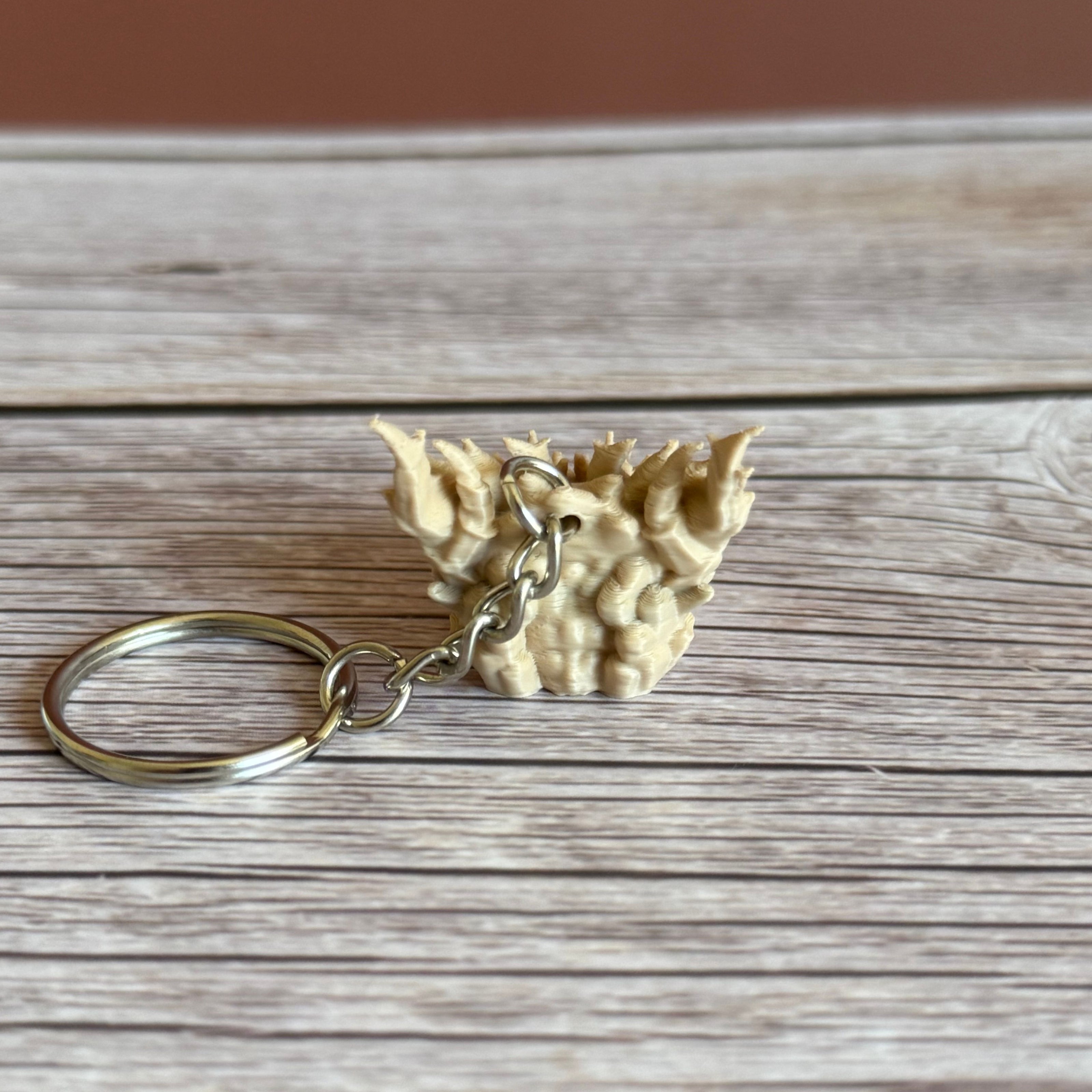 Back of a 3D printed beige dragon head keychain on a wooden surface