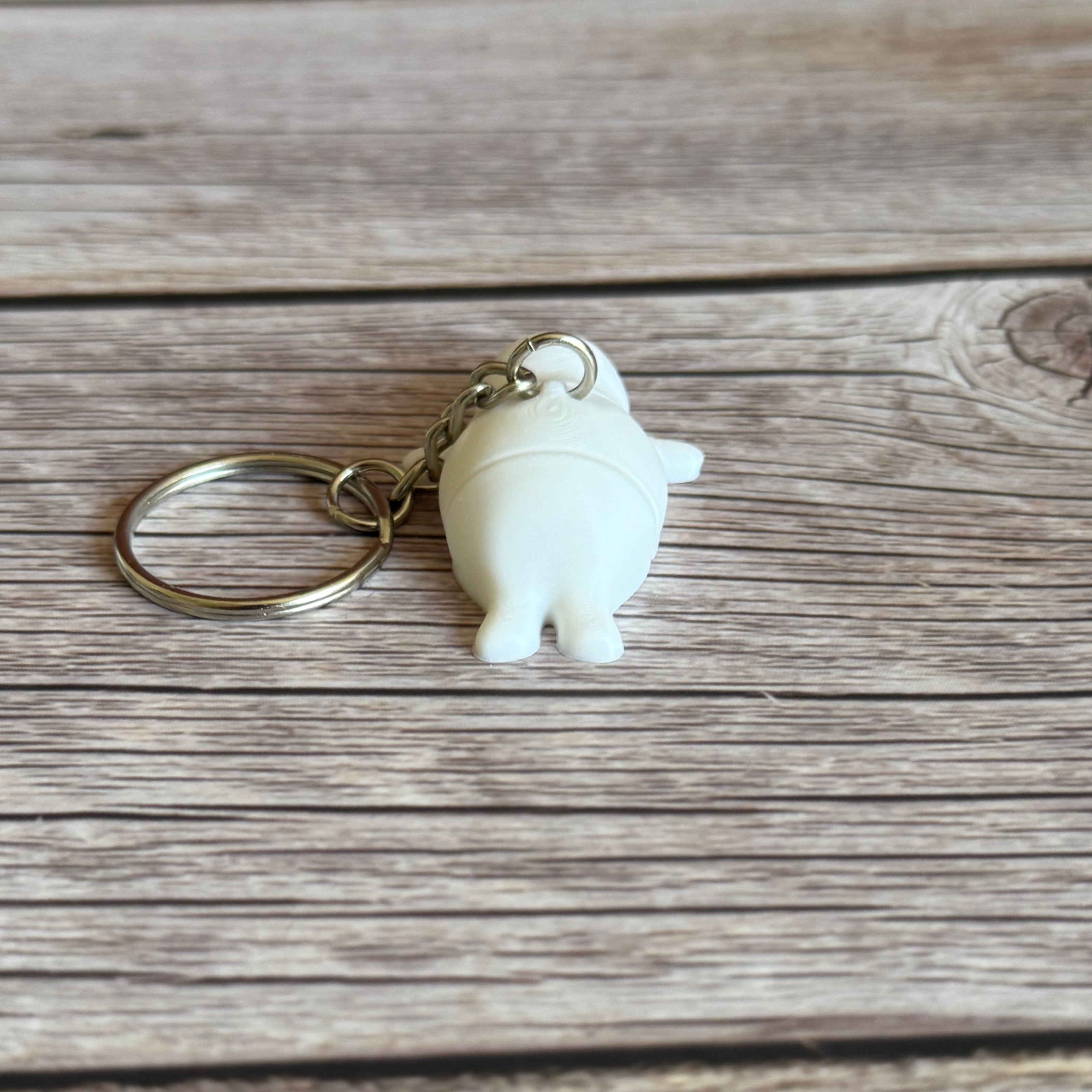 Back of a 3D printed white seal-shaped keychain on a wooden surface