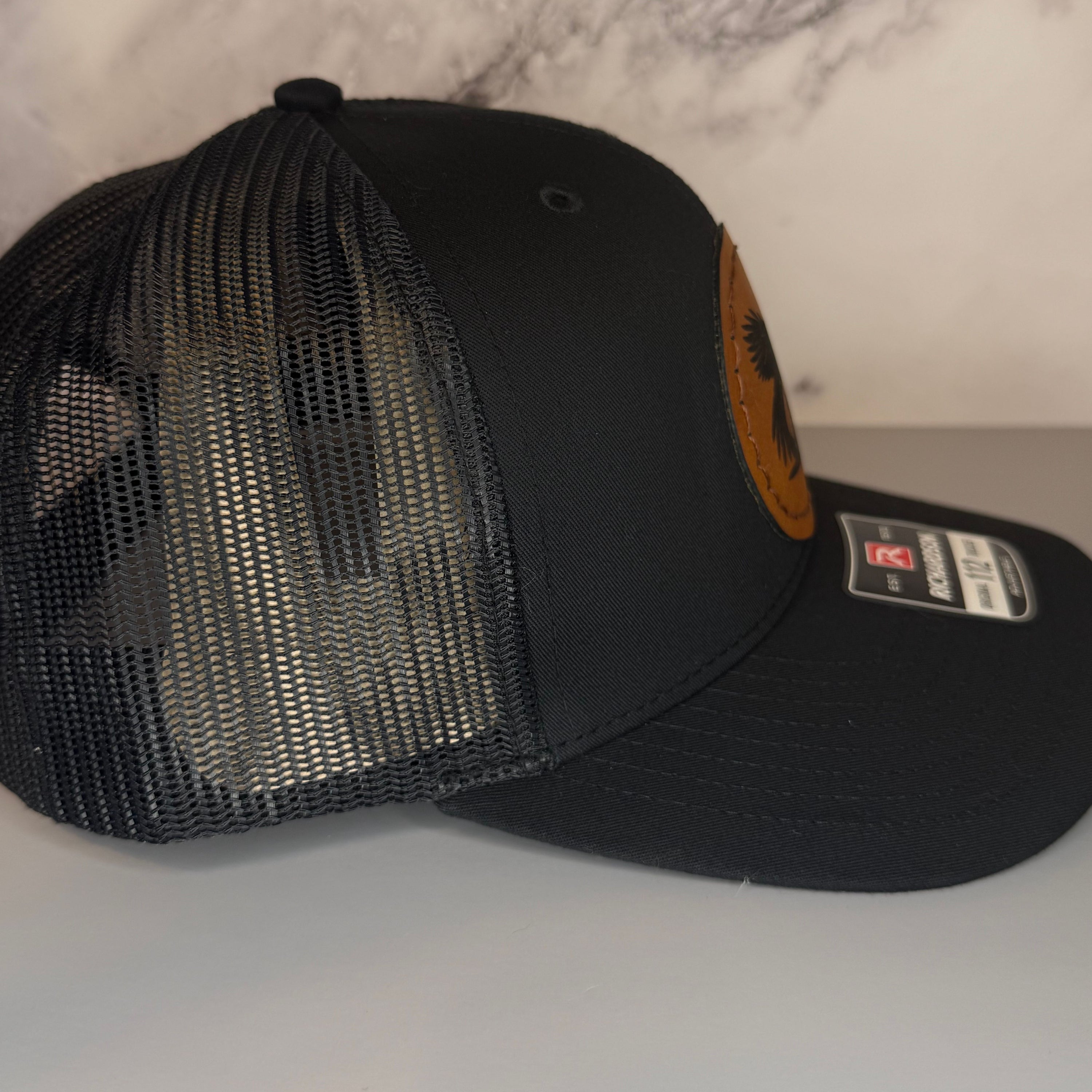 Black mesh cap with a leather patch on a gray surface