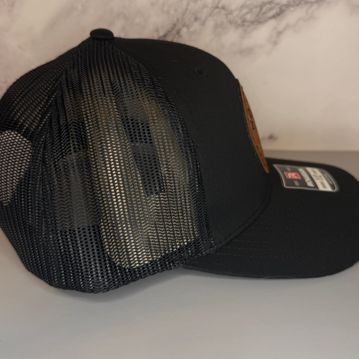 Black mesh cap with a brand label on a light gray background