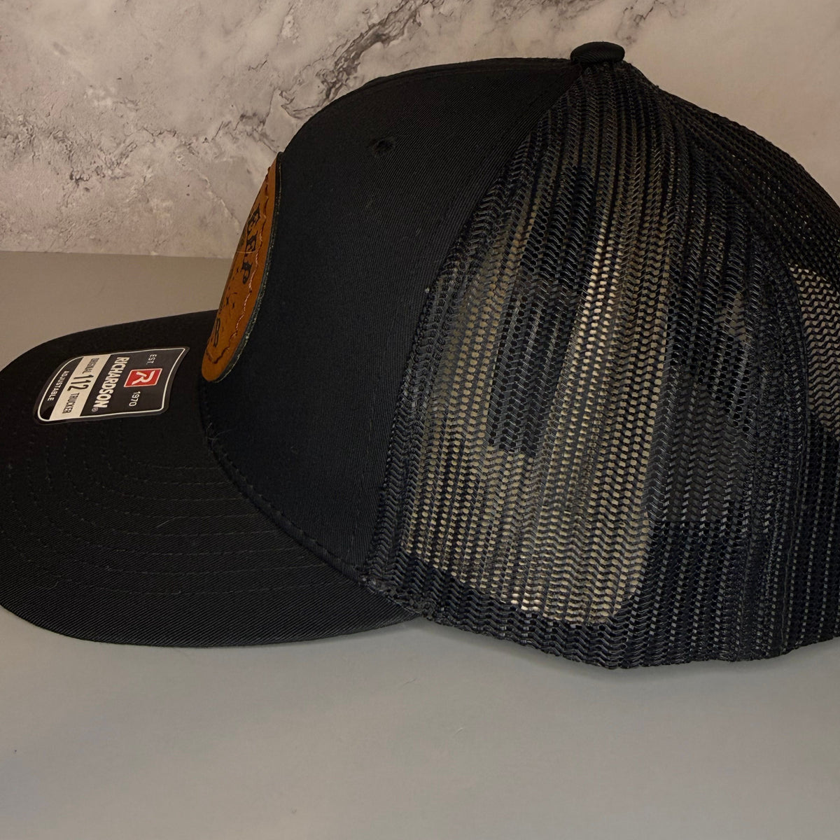 Black mesh cap on a light gray surface with a marble-patterned wall in the background