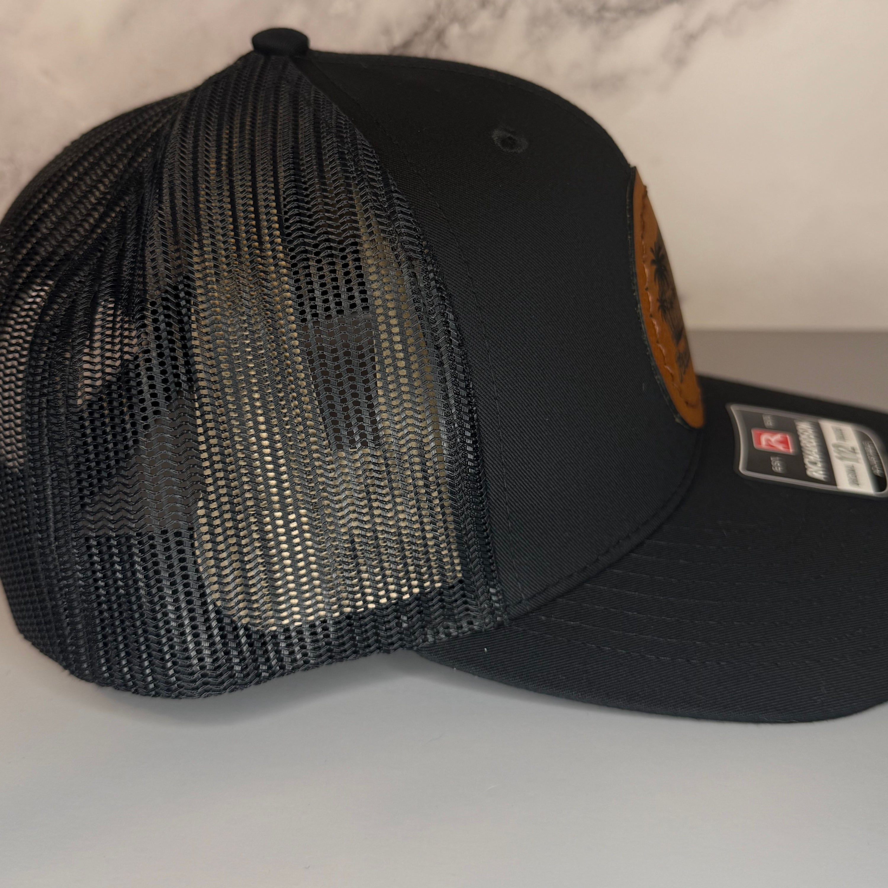 Black mesh cap with a brand logo on a light gray background