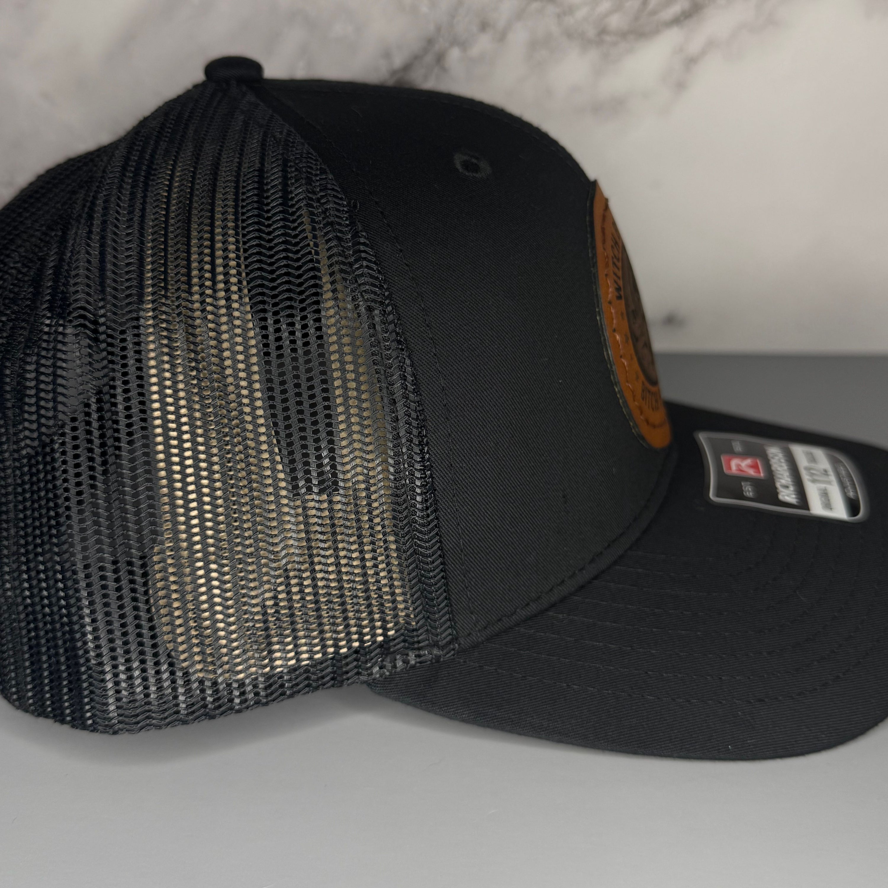 Black mesh cap with leather patch on a gray surface