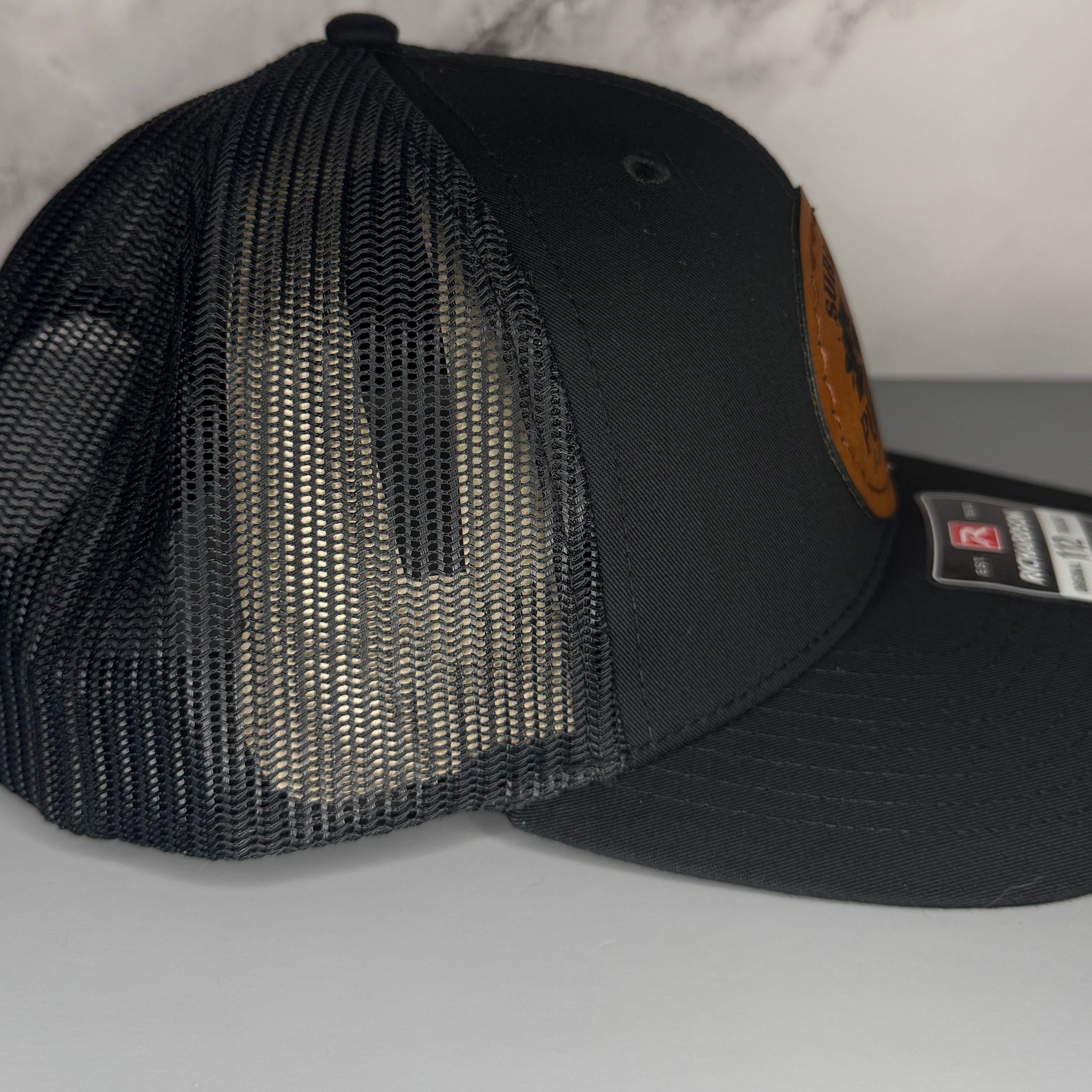 Black mesh cap with a brand label on a gray surface
