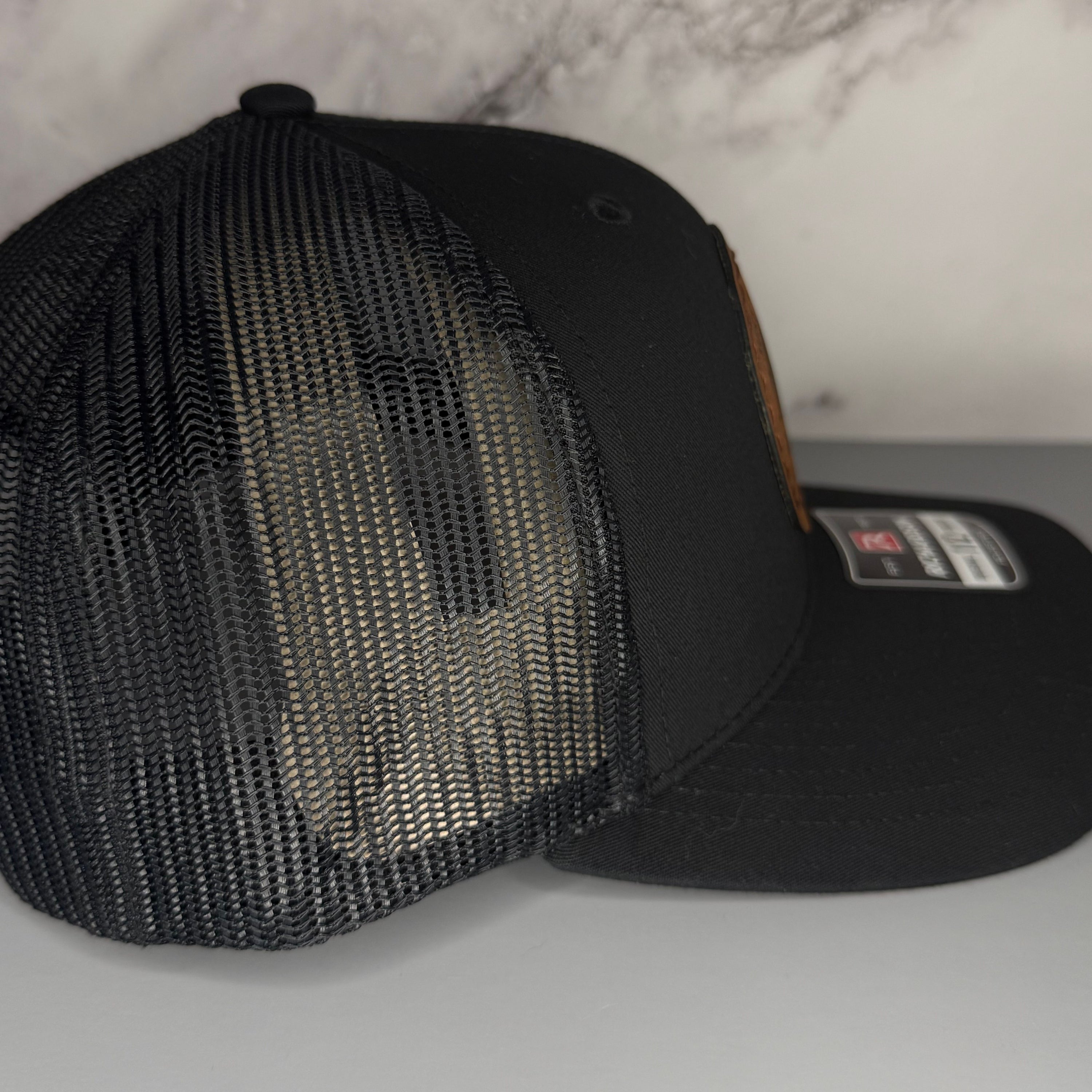 Black mesh cap on a light gray surface with a gray background