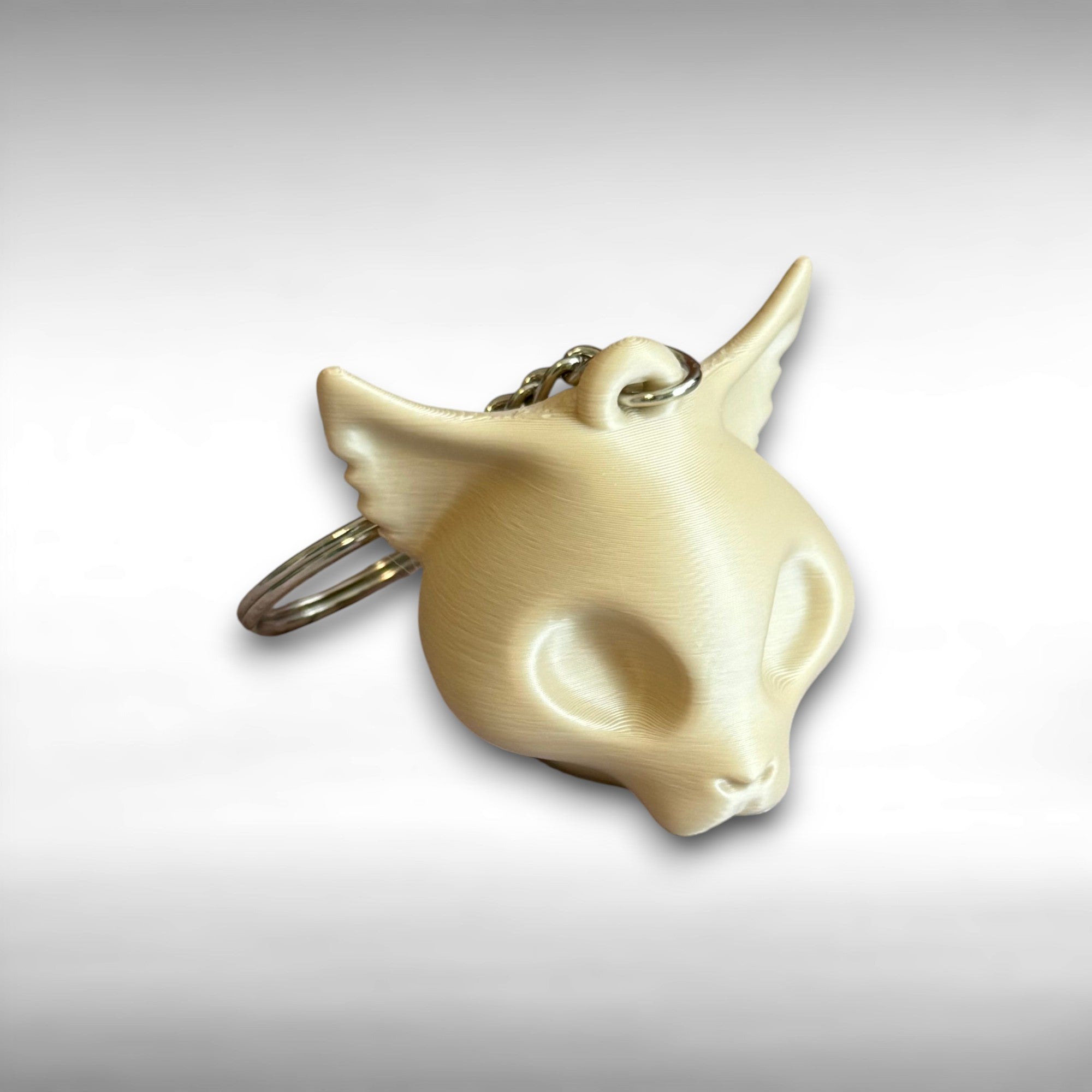3D printed beige cat skull-shaped keychain against a white background