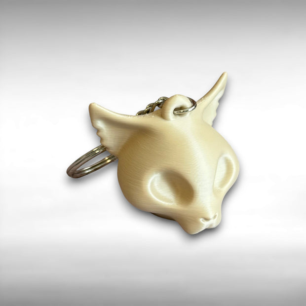 3D printed beige cat skull-shaped keychain against a white background