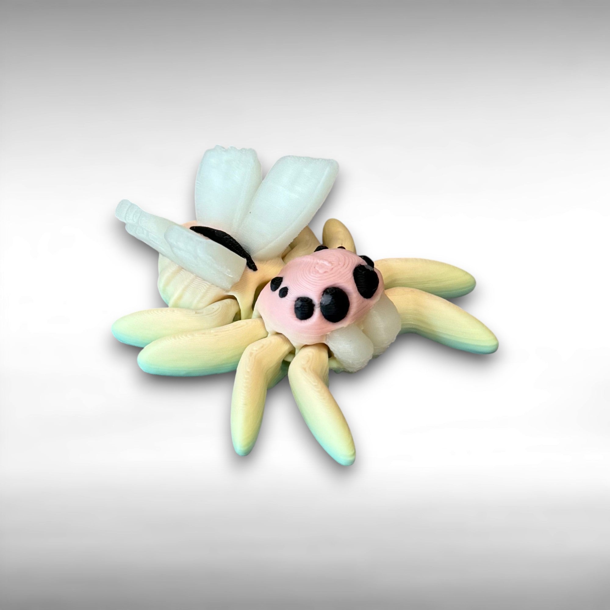 3D printed small spider with fairy design featuring rainbow coloring and white wings against a white background