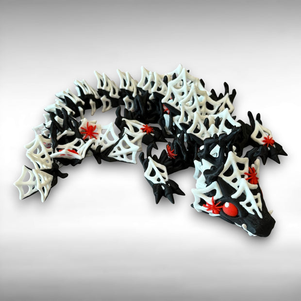 3D printed black dragon with white spider webs and red spiders across the body against a gray background