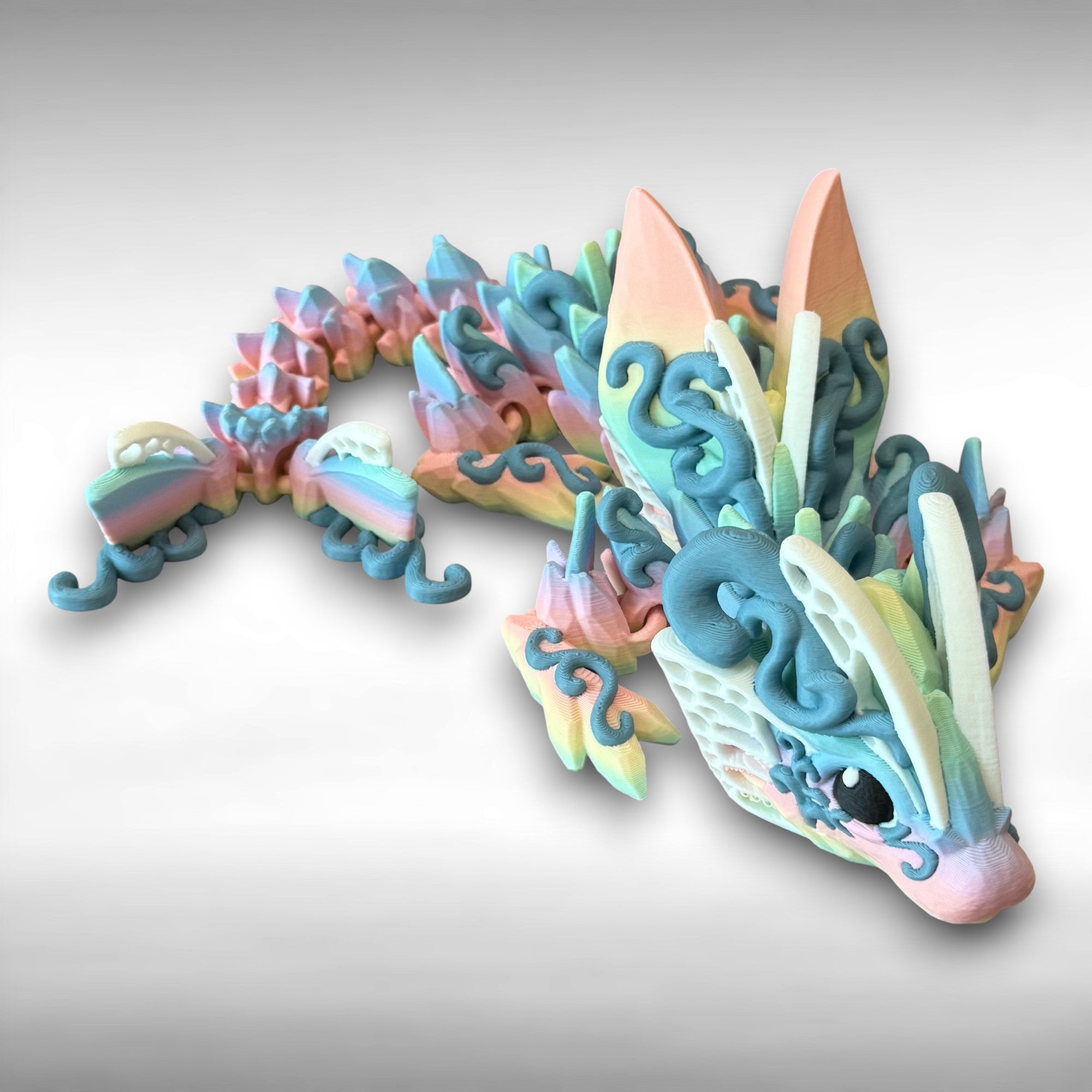 A 3D printed articulated fantasy creature resembling a dragon with butterfly features, in multicolor design, against a white background