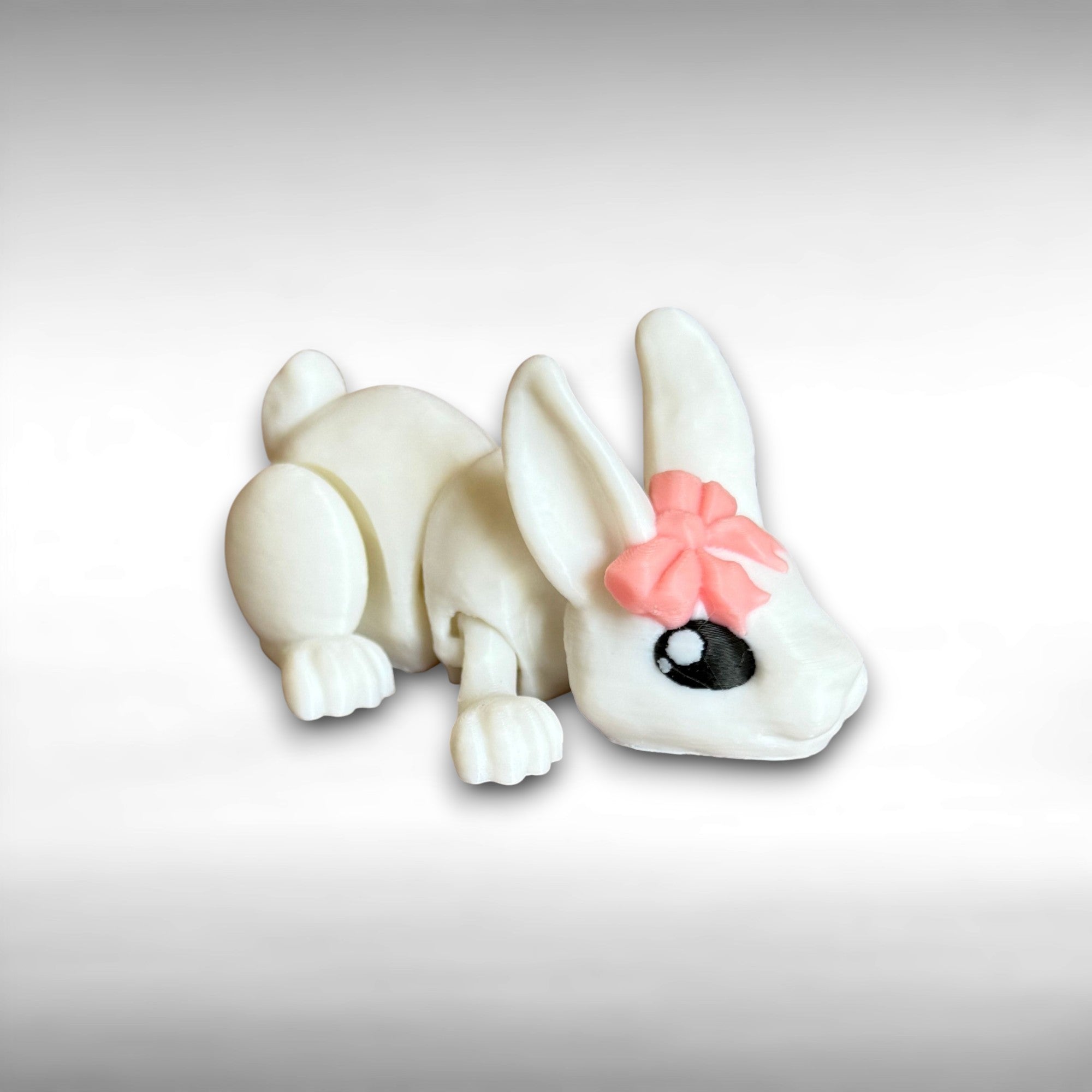 3D printed white rabbit figurine with a pink bow on a light gray background