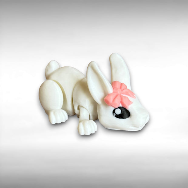 3D printed white rabbit figurine with a pink bow on a light gray background