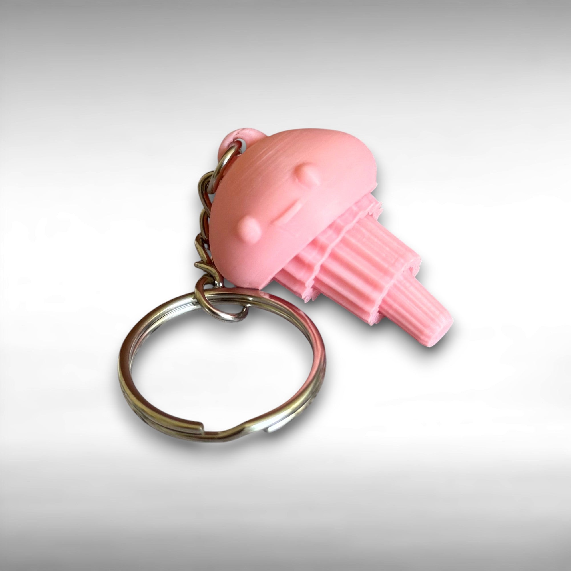 3D Printed pink jellyfish-like keychain with a smiling face against a white background