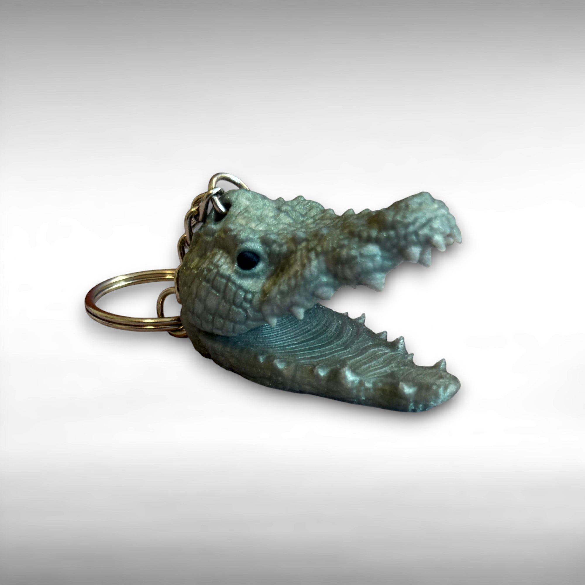 3D printed shimmer green crocodile head-shaped keychain on a white background