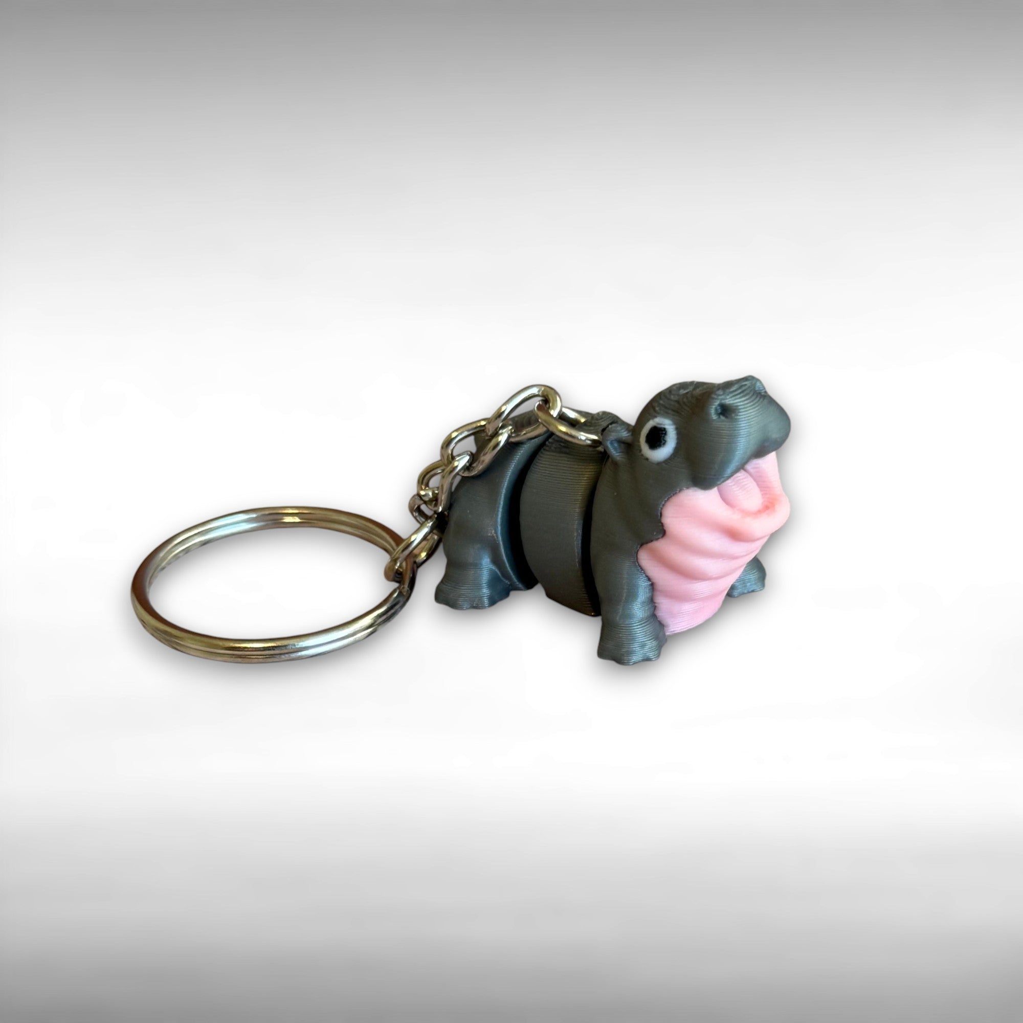 3D printed gray and pink hippo-shaped keychain on a light gray background