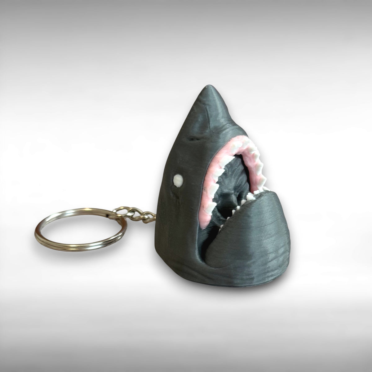 3D printed gray shark-head keychain against a white background