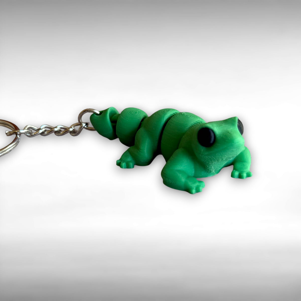 3D printed green lizard-shaped keychain on a light gray background