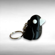 3D printed black and white crow-shaped keychain on a light gray background