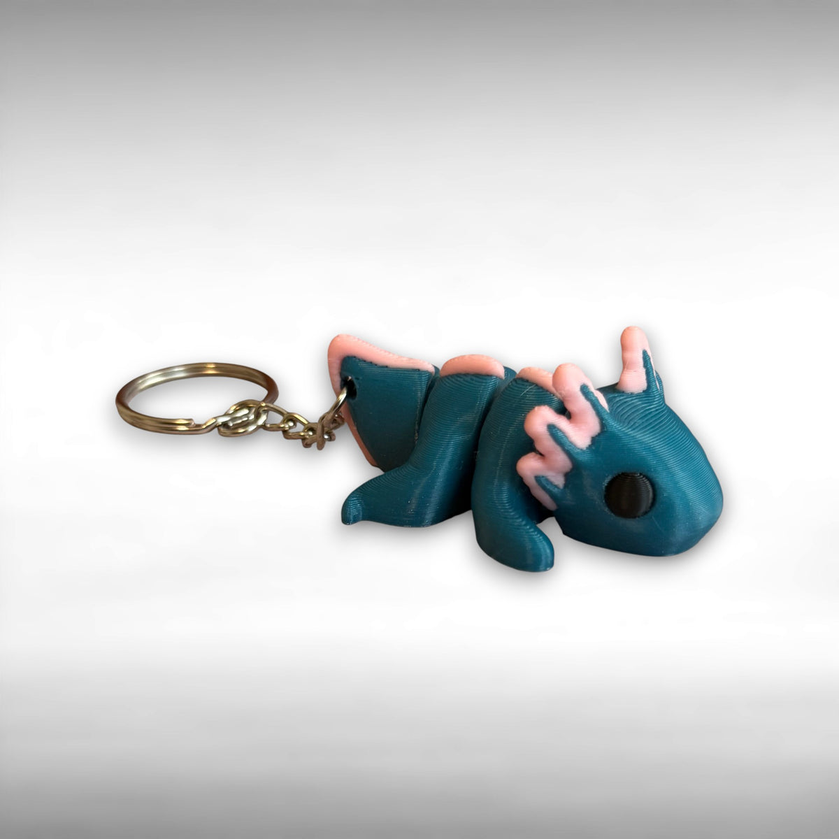 3D printed blue and pink axolotl-shaped keychain on a light gray background