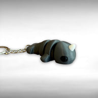 3D printed gray narwhal-shaped keychain on a light gray background