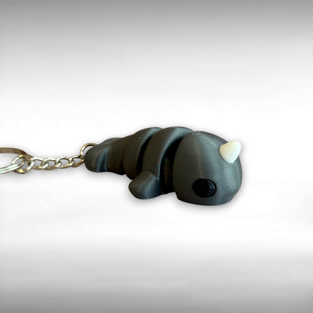 3D printed gray narwhal-shaped keychain on a light gray background