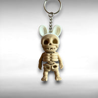 3D printed keychain of a beige skeleton with white bunny ears against a white background