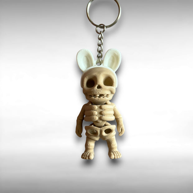 3D printed keychain of a beige skeleton with white bunny ears against a white background