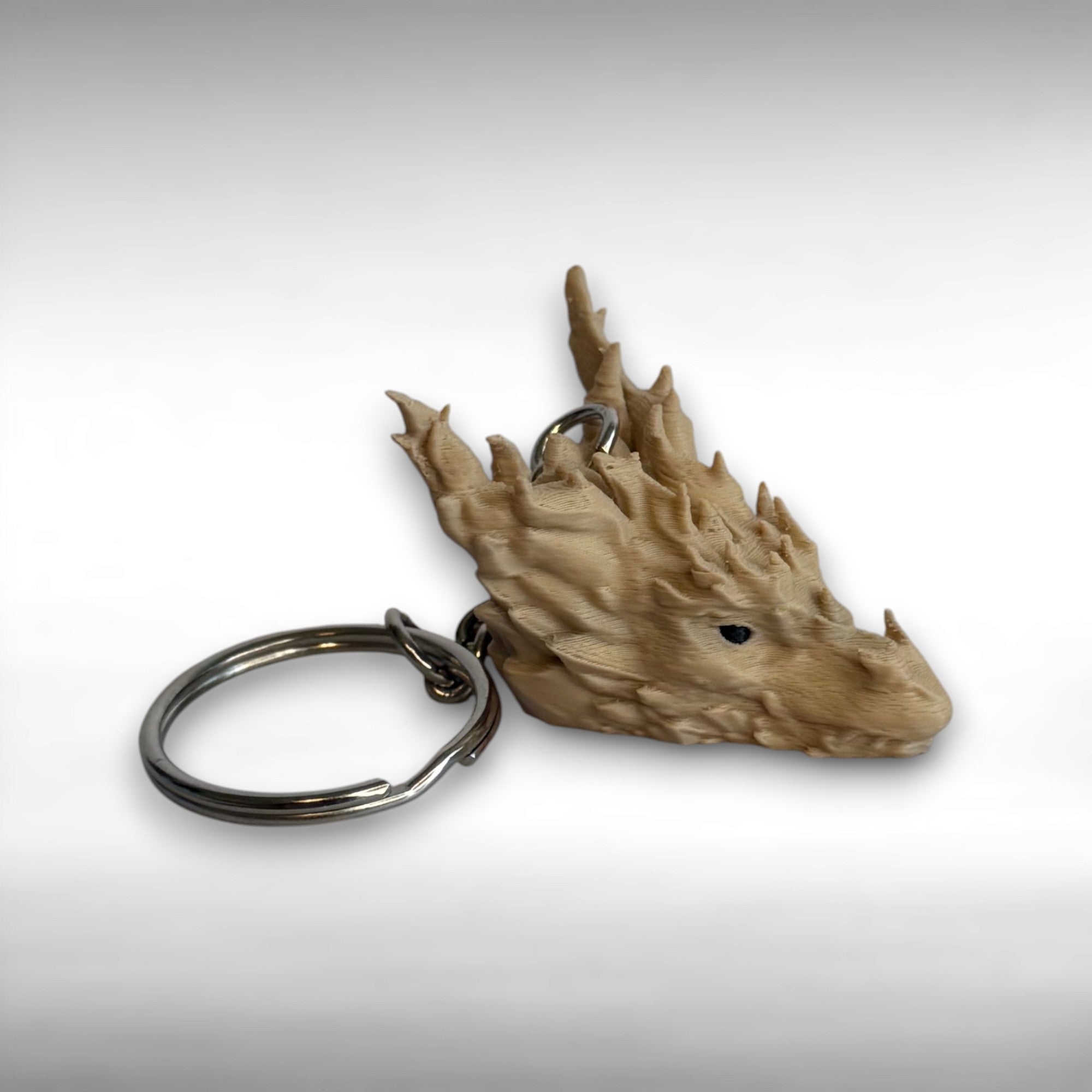 3D printed beige dragon head keychain on a white background