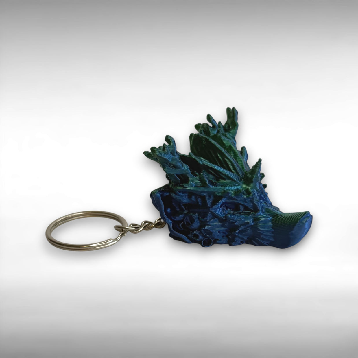 3D printed blue and green coral reef themed dragon-head keychain on a white background
