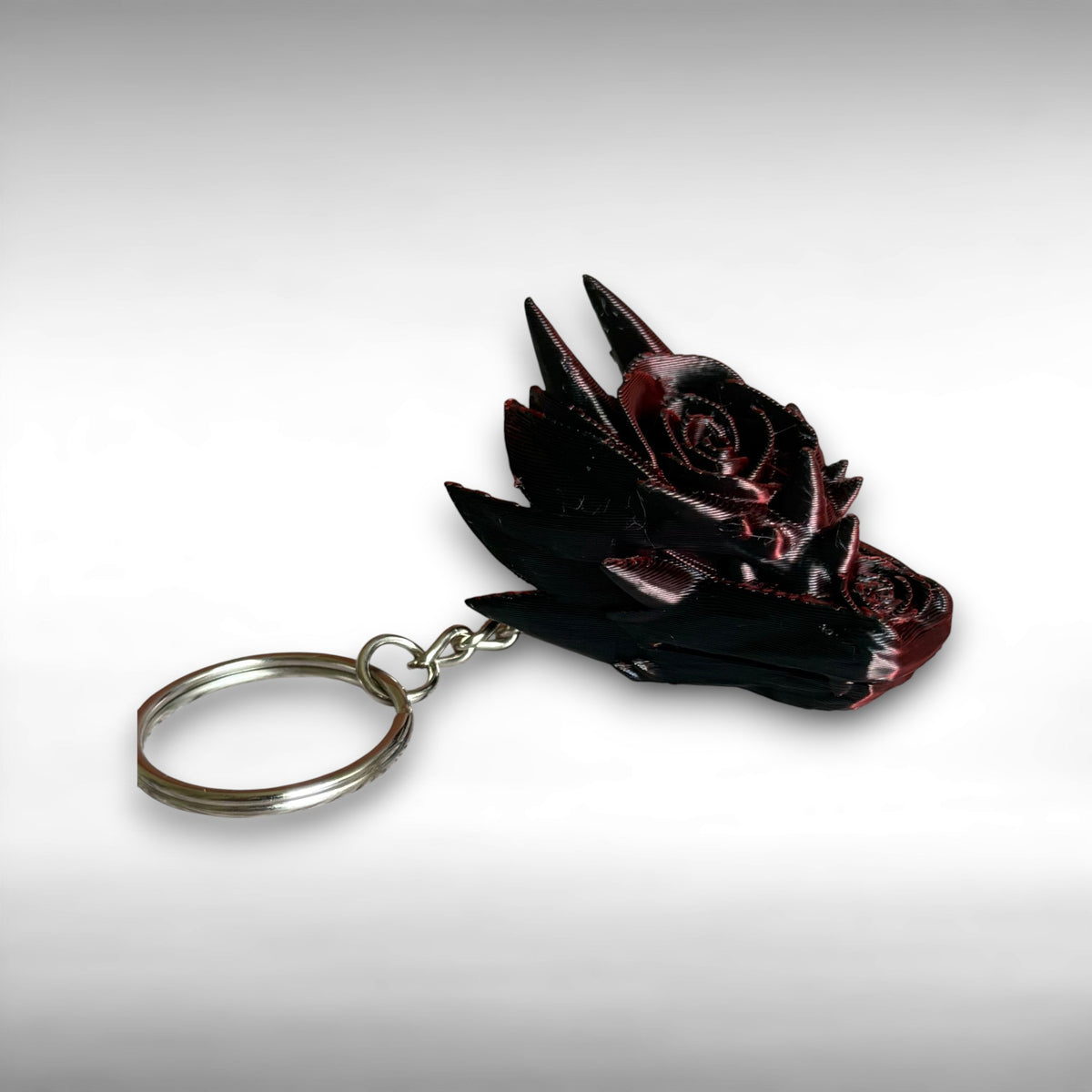 3D printed red and black dragon head keychain with a rose design on a white background