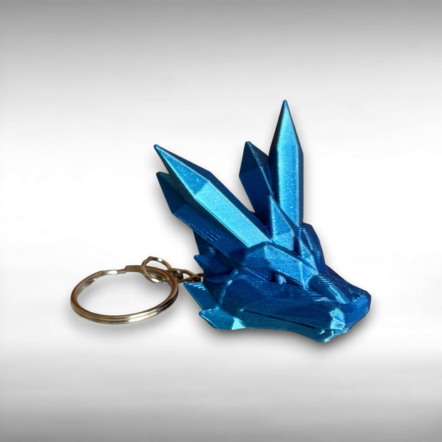 blue 3D printed keychain shaped like a dragon head with crystal-like details, against a white background