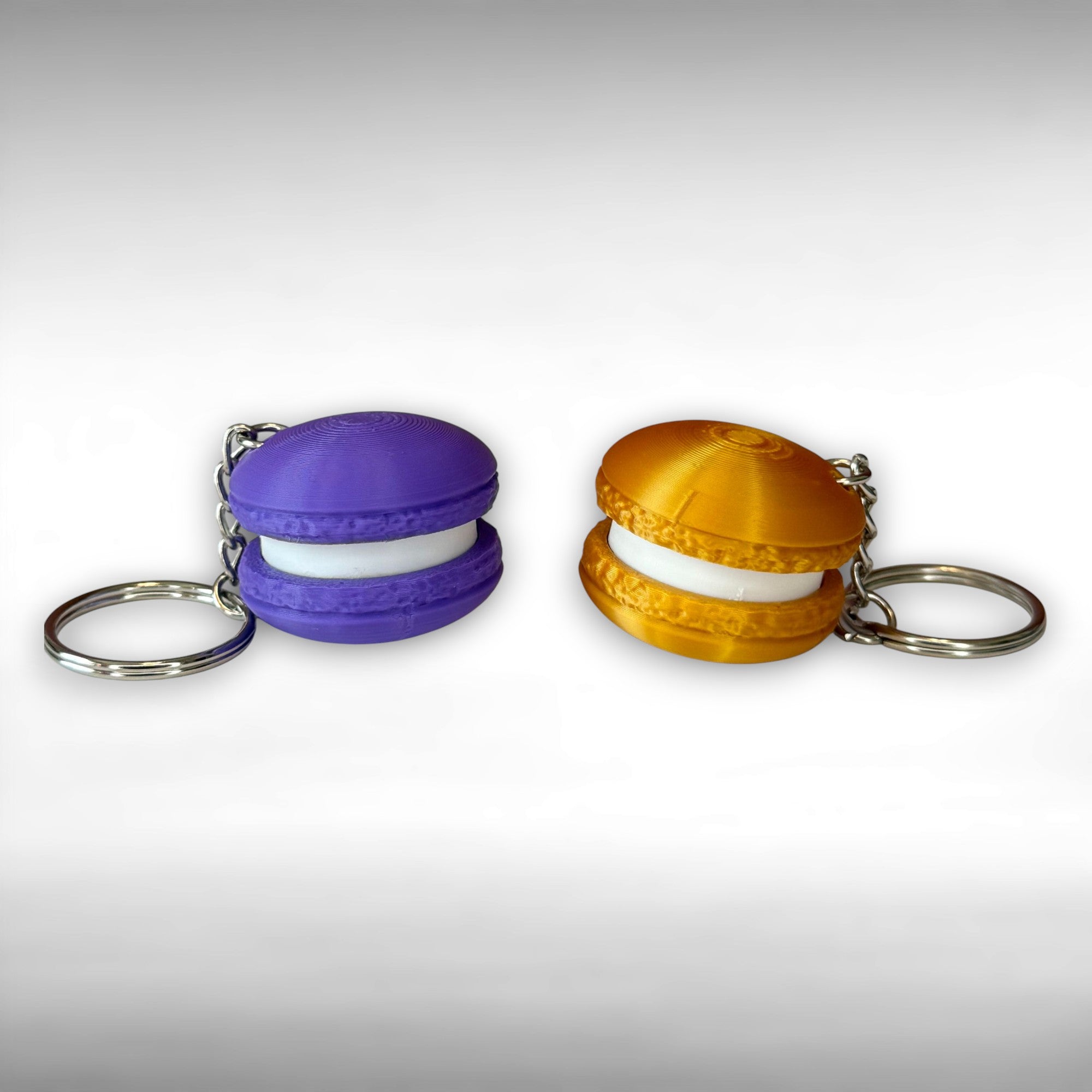 Purple and gold 3D printed macaron-shaped keychains on a white background