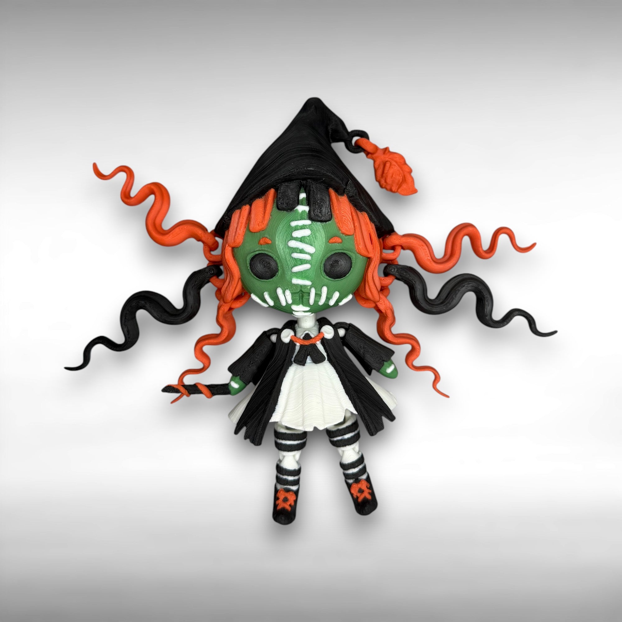 Toy figure with green face, black hood, and orange hair on a gray background