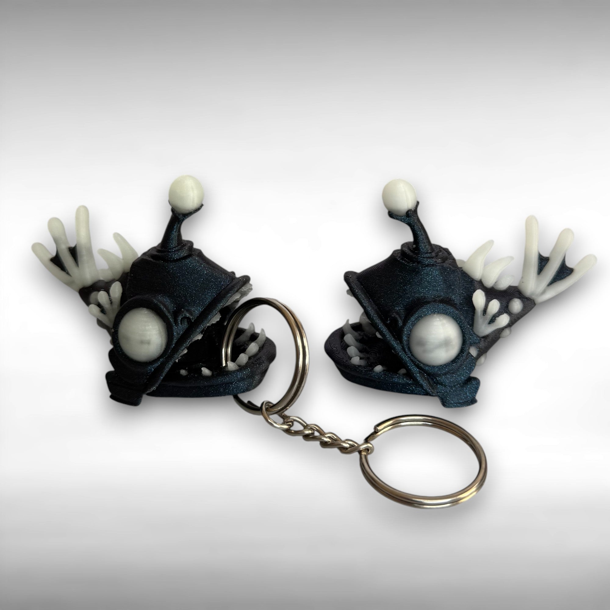 Sparkly blue angler fish keychain and figurine with white accents on a gray background