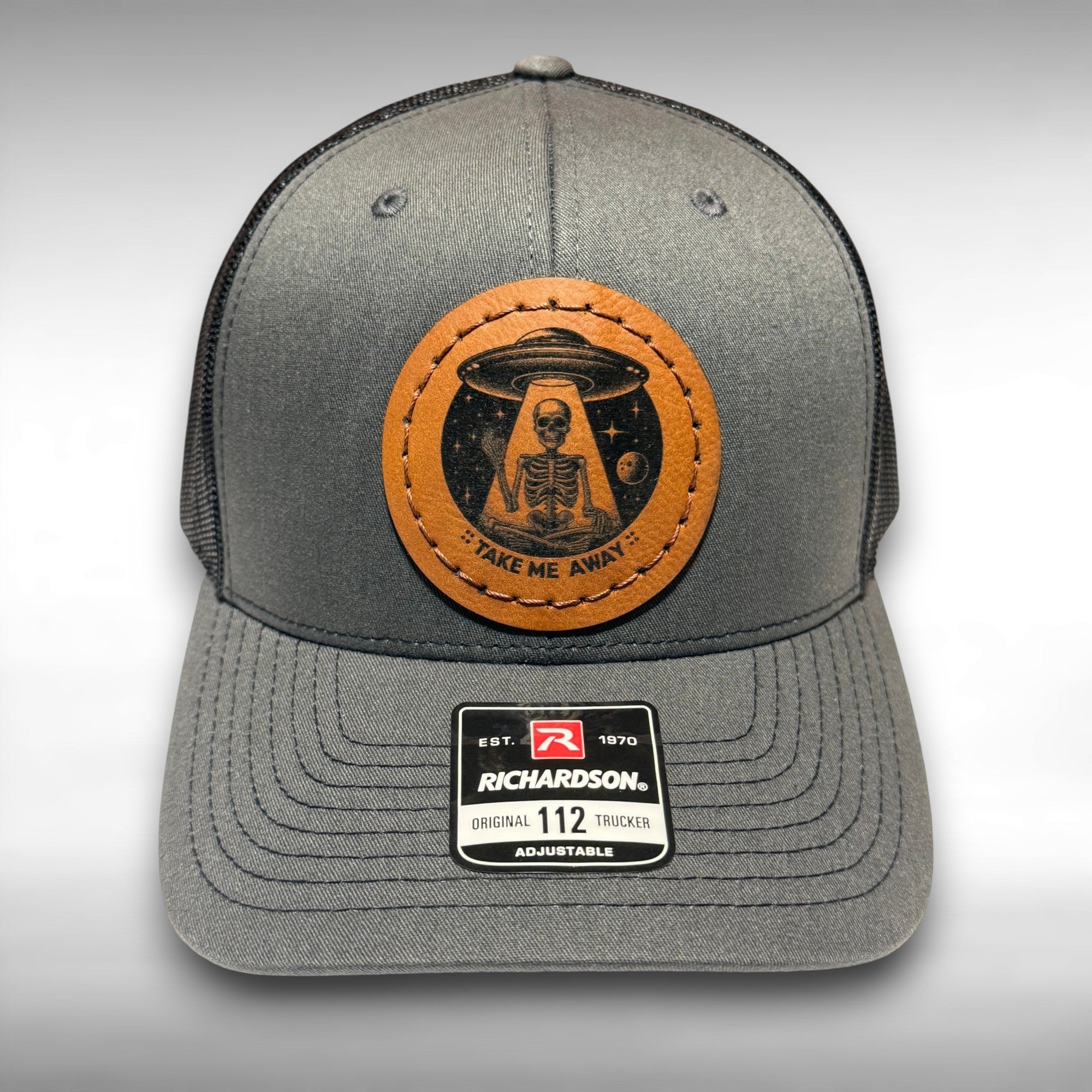 Gray trucker hat with a image of a skeleton and UFO with the phrase 