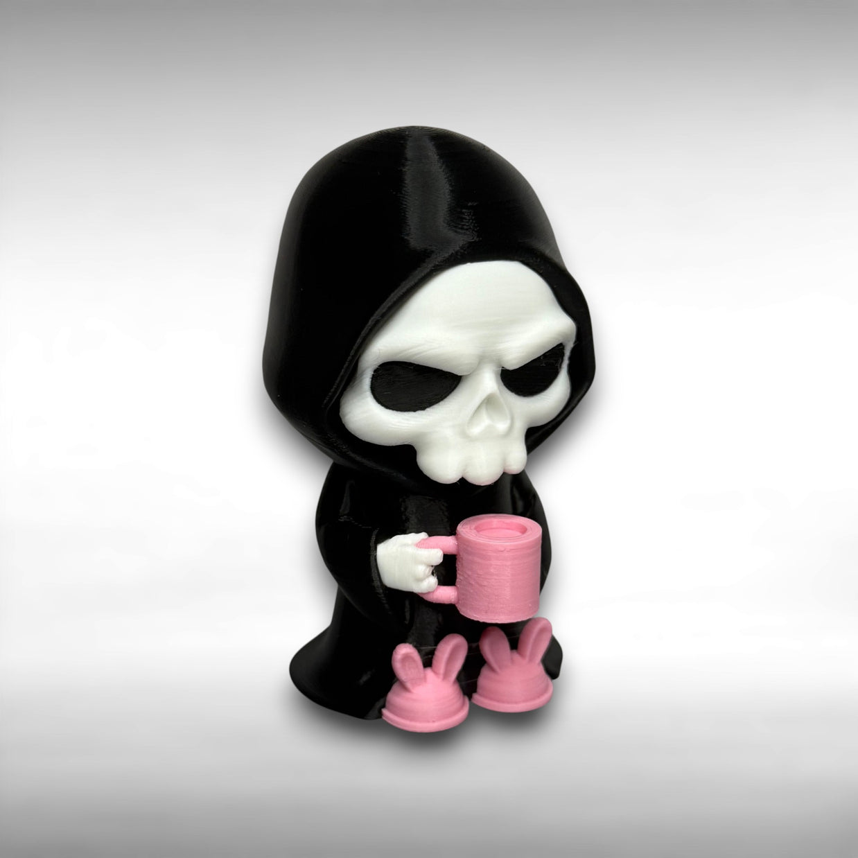 Skull-like figure in a black hood and pink slippers holding a pink mug on a gray background