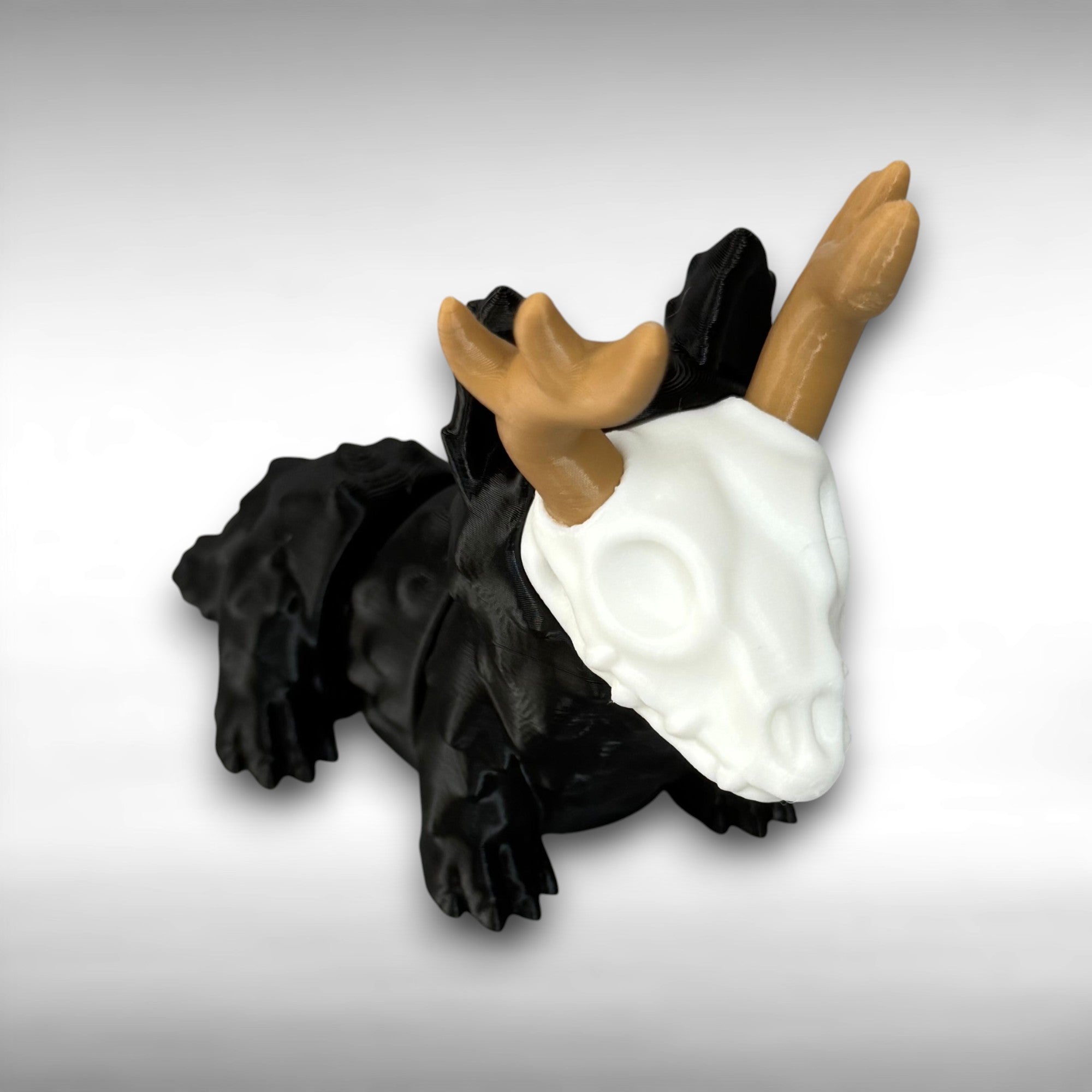 Four-legged black animal-shaped figure with antlers and a skull face on a gray background