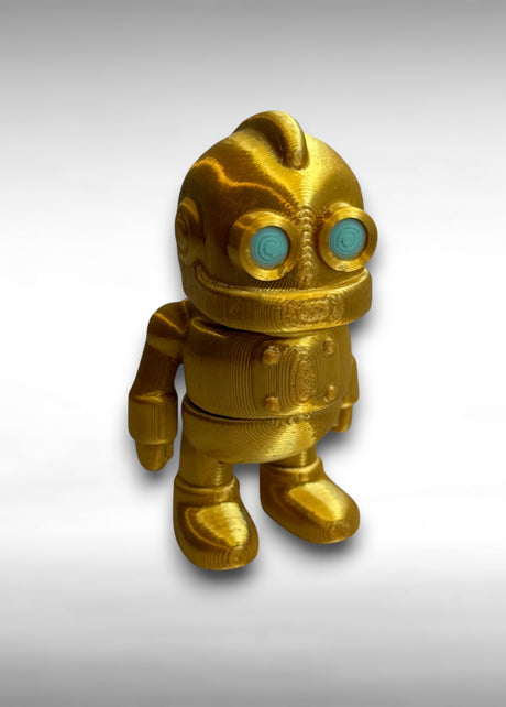Gold robot toy with turquoise eyes on a gray background