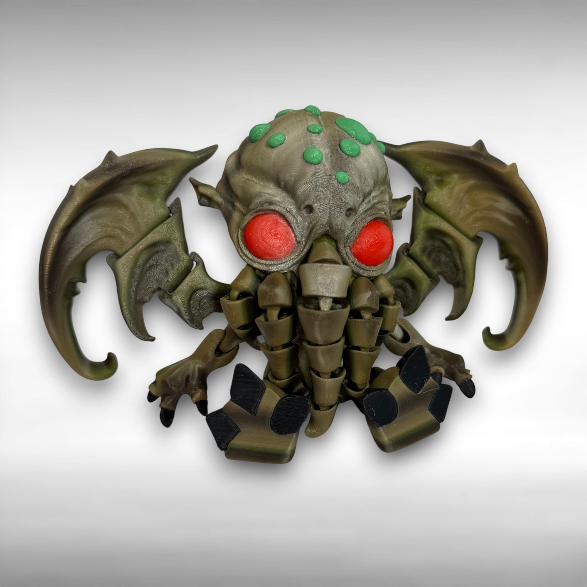 Toy figure of a creature with red eyes and green accents on a gray background