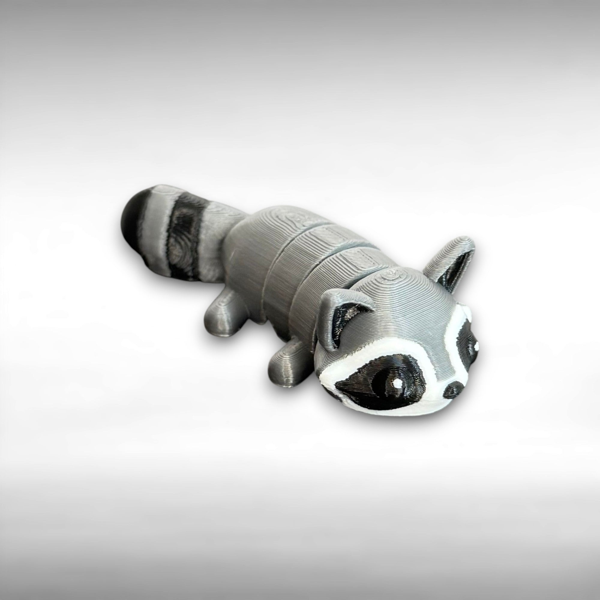 3D-printed raccoon toy on a gray background