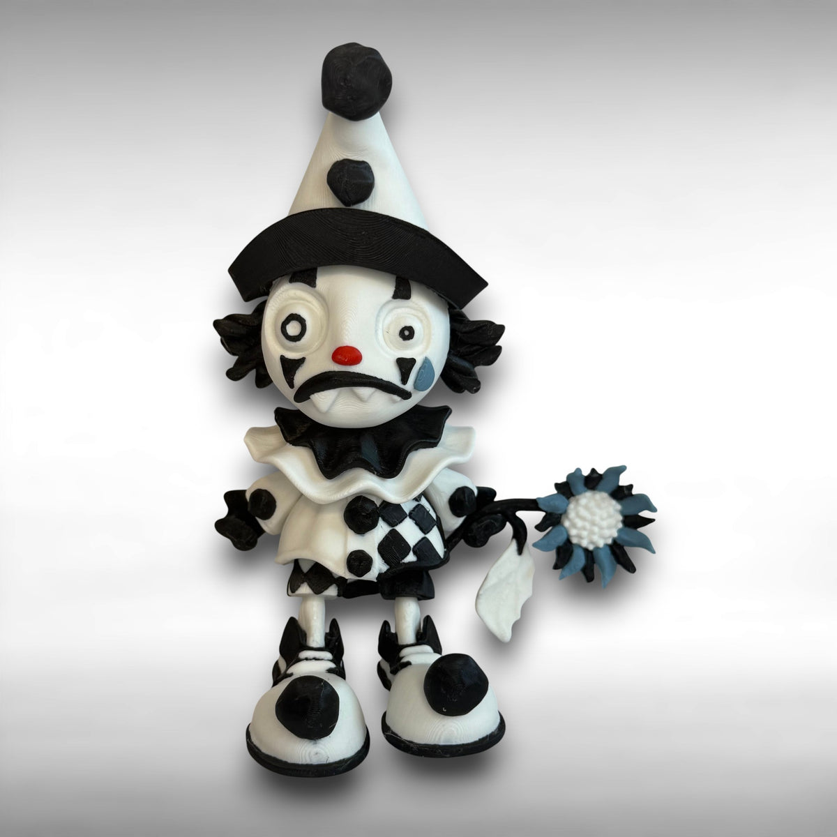 Black and white clown figurine with a hat and checkered outfit on a gray background
