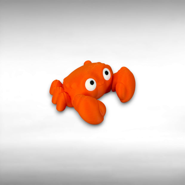 A 3D printed mini articulated orange crab fidget toy with articulated claws, placed on a light surface.