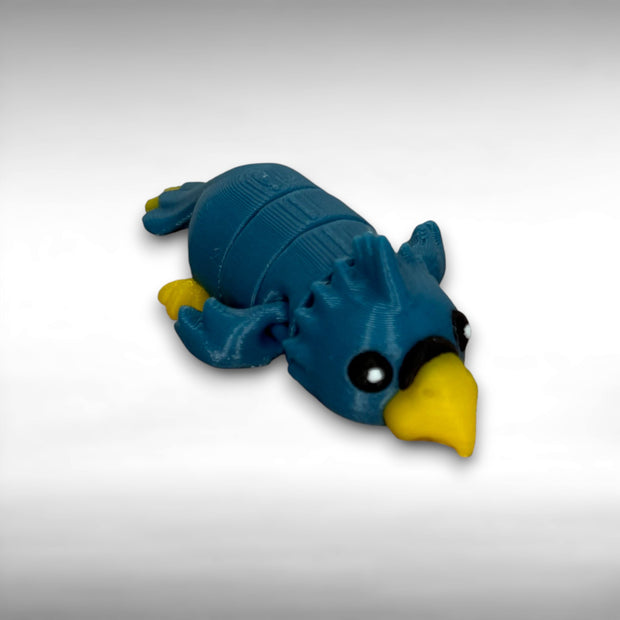 A small 3D printed blue and yellow articulated mini parrot toy on a white background