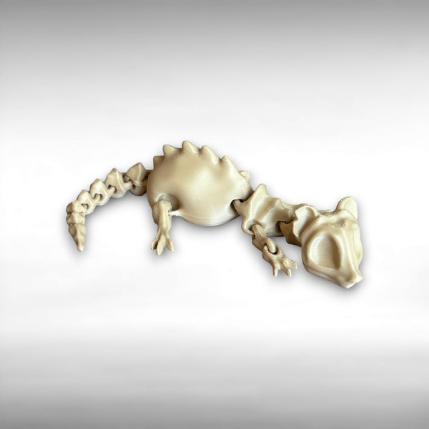 A small beige 3D printed articulated rat skeleton figurine against a white background