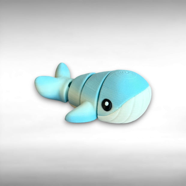 A small 3D printed articulated mini blue and white whale toy with articulated segments on a white background