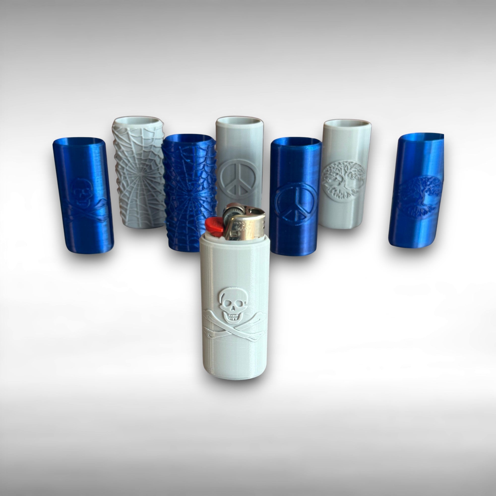 A collection of 3D printed Bic lighter cases with various designs such as Spider Web, Skull and Crossbones, Tree of Life, and Peace Sign, displayed in blue and gray colors.
